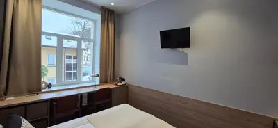 a bedroom with a tv on the wall and a window at Cozy Private Room in Corner Building in Vilnius