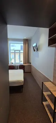 a hotel room with a bed and a window at Cozy Private Room in Corner Building in Vilnius