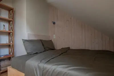 a bed in a room with a wooden wall at Panekelpių vienkiemis in Aguriškės