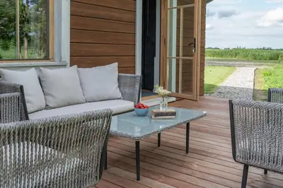 a porch with a couch and chairs and a table at Panekelpių vienkiemis in Aguriškės