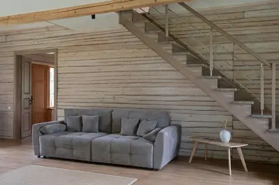 a living room with a couch and a staircase at Panekelpių vienkiemis in Aguriškės