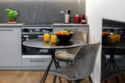 a table with a bowl of fruit and glasses of orange juice at Cozy Top-Floor Apartment with City Views Vilnius in Vilnius