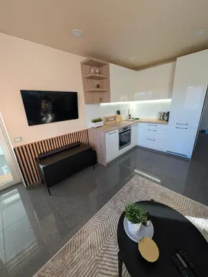 a living room with a table and a kitchen at Jaukūs apartamentai prie Šiaulių arenos in Šiauliai