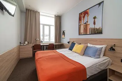a bedroom with a large bed with an orange blanket at Hotel Premium Rooms in Vilnius