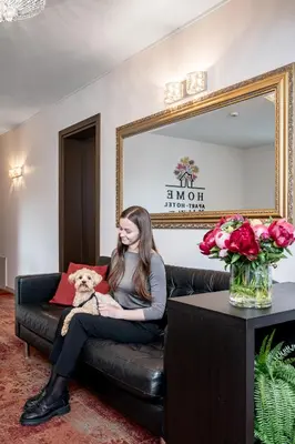 a woman sitting on a couch holding a dog at HOME Studios & Apartments Old town 10 min walk 24-hours Front desk Vilnius in Vilnius