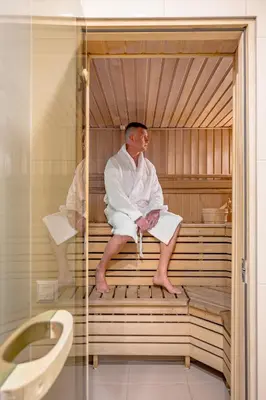 a man sitting in a sauna in a bath tub at HOME Studios & Apartments Old town 10 min walk 24-hours Front desk Vilnius in Vilnius