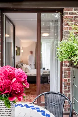 a table with a vase of flowers on a patio at HOME Studios & Apartments Old town 10 min walk 24-hours Front desk Vilnius in Vilnius