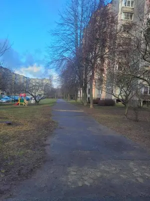 an empty path in a park with trees and a building at Šiaurės Butas in Kaunas