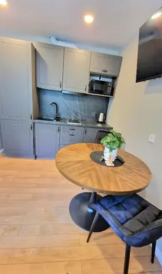 a kitchen with a wooden table and a table and a table sidx sidx at Trumpalaikė butų nuoma Kaune prie Klinikų STUDIJA B SELF CHECK IN in Kaunas