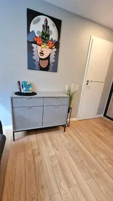 a living room with a table and a painting on the wall at Trumpalaikė butų nuoma Kaune prie Klinikų STUDIJA B SELF CHECK IN in Kaunas