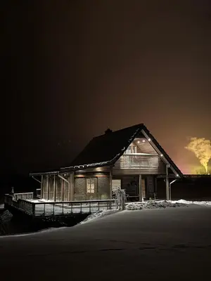 a wooden house at night in the snow at Pakarklių sodyba in Šeiminiškiai