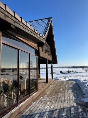 a wooden house with large windows on a snow covered field at Pakarklių sodyba in Šeiminiškiai