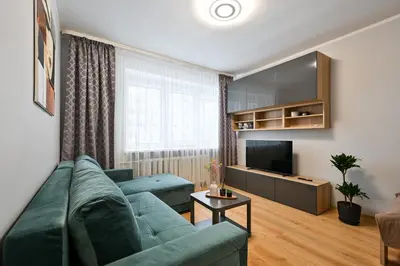 a living room with a green couch and a television at City Essetials Apartmets in Kaunas