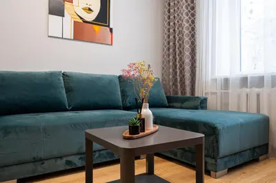 a living room with a green couch and a table at City Essetials Apartmets in Kaunas