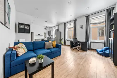 a living room with a blue couch and a table at Spacious and Bright Lukiskiu Square Apartment in Vilnius