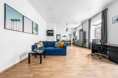 a living room with a blue couch and a desk at Spacious and Bright Lukiskiu Square Apartment in Vilnius