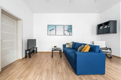 a living room with a blue couch and a tv at Spacious and Bright Lukiskiu Square Apartment in Vilnius