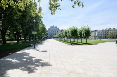 a sidewalk in a park with trees and buildings at Spacious and Bright Lukiskiu Square Apartment in Vilnius