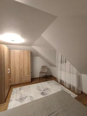 an attic room with a bed and a chair at Cozy City Attic in Šiauliai
