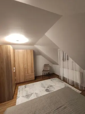 an attic room with a bed and wooden cabinets at Cozy City Attic in Šiauliai