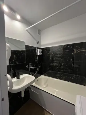 a black tiled bathroom with a sink and a bath tub at Kerulis Apartments in Vilnius