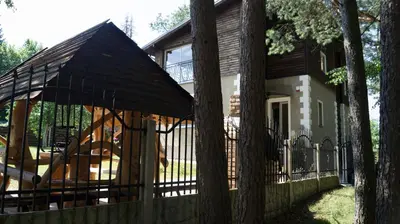 a house with a fence and an umbrella at Raigardo in Druskininkai