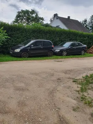 two cars parked on the side of a driveway at Hostel in Rudamina