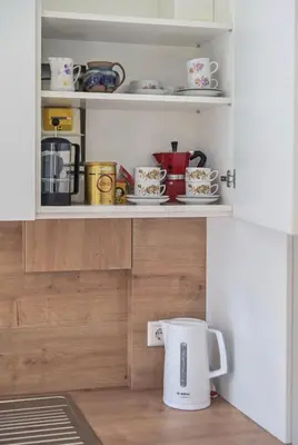 a cupboard filled with cups and plates and a coffee pot at Warm and Timeless- Authentic Vintage Living in Paupys in Vilnius