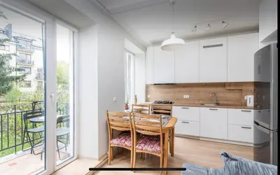 a kitchen with white cabinets and a table with chairs at Warm and Timeless- Authentic Vintage Living in Paupys in Vilnius
