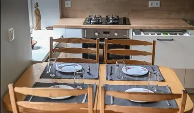 a wooden table with four chairs and a kitchen at Warm and Timeless- Authentic Vintage Living in Paupys in Vilnius