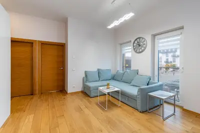 a living room with a blue couch and a clock at Center apartment by Polo Apartments in Kaunas