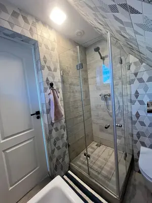 a shower with a glass door in a bathroom at Cozy and quiet apartment near the city in Kaunas