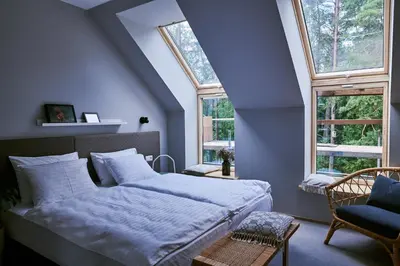 a bedroom with a large bed and two windows at Barono Vila in Butėnai