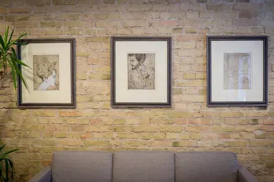 three framed pictures on a brick wall with a couch at Green apple - Self check-in - Free parking in Vilnius