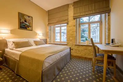 a bedroom with a bed and a desk and windows at Green apple - Self check-in - Free parking in Vilnius