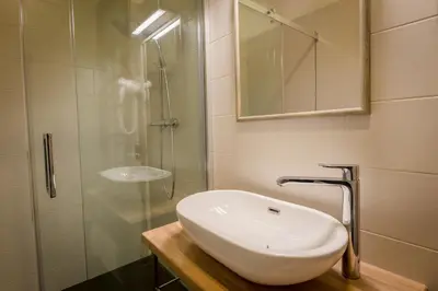a bathroom with a sink and a glass shower at Green apple - Self check-in - Free parking in Vilnius