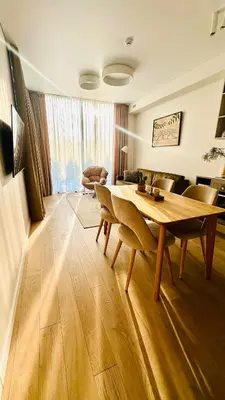 a living room with a wooden table and chairs at Cozy Riverside Apartment in Birštonas