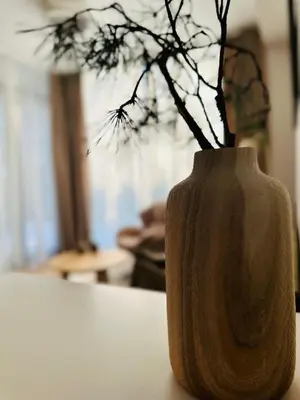 a wooden vase with a plant in it on a table at Cozy Riverside Apartment in Birštonas