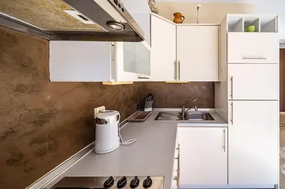a kitchen with white cabinets and a sink at Guido apartament in Šiauliai