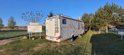 a trailer parked in a field next to a sign at Vigio Brasta camping in Elektrėnai