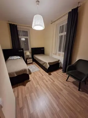 a bedroom with two beds and a chair and a chandelier at Aguona namai apartamentai in Kaunas
