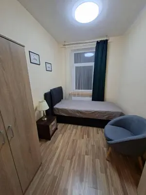 a bedroom with a bed and a chair and a window at Aguona namai apartamentai in Kaunas