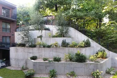 a stone retaining wall with a garden in front of a building at New Cozy Designer Apartment in Uzupis Walk to Old Town in a Luxury Building Garden View Balcony in Vilnius