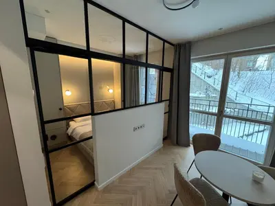 a room with a table and a bed and a window at New Cozy Designer Apartment in Uzupis Walk to Old Town in a Luxury Building Garden View Balcony in Vilnius