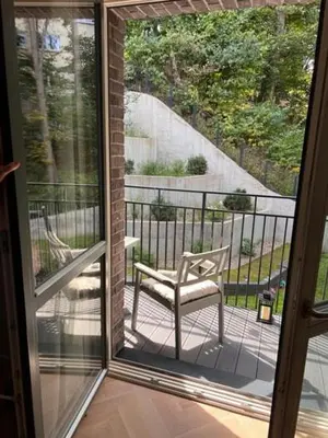 a sliding glass door with a chair on a balcony at New Cozy Designer Apartment in Uzupis Walk to Old Town in a Luxury Building Garden View Balcony in Vilnius