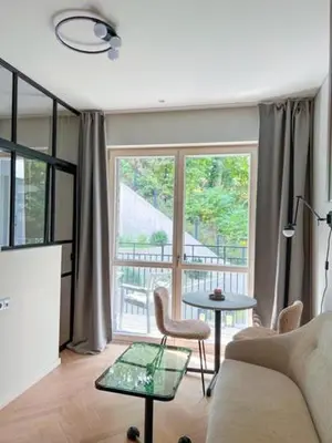 a living room with a couch and a table and a window at New Cozy Designer Apartment in Uzupis Walk to Old Town in a Luxury Building Garden View Balcony in Vilnius