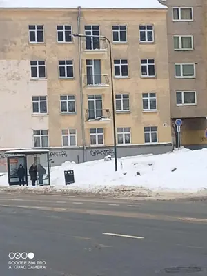 two people standing at a bus stop in front of a building at Frankes Cozy One Bedroom Apartment in Vilnius