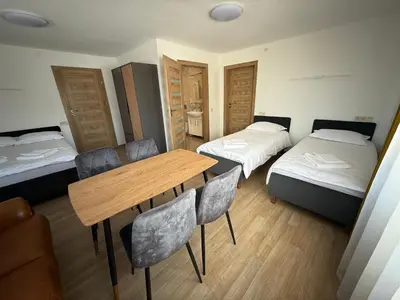 a room with two beds and a table and chairs at SALGIRDO svečių namai in Kelmė