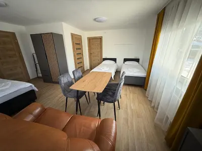 a room with a couch and a table and a bed at SALGIRDO svečių namai in Kelmė