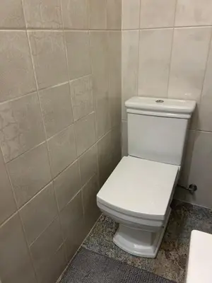 a white toilet in a bathroom with a tiled wall at City Park Apartment in Vilnius